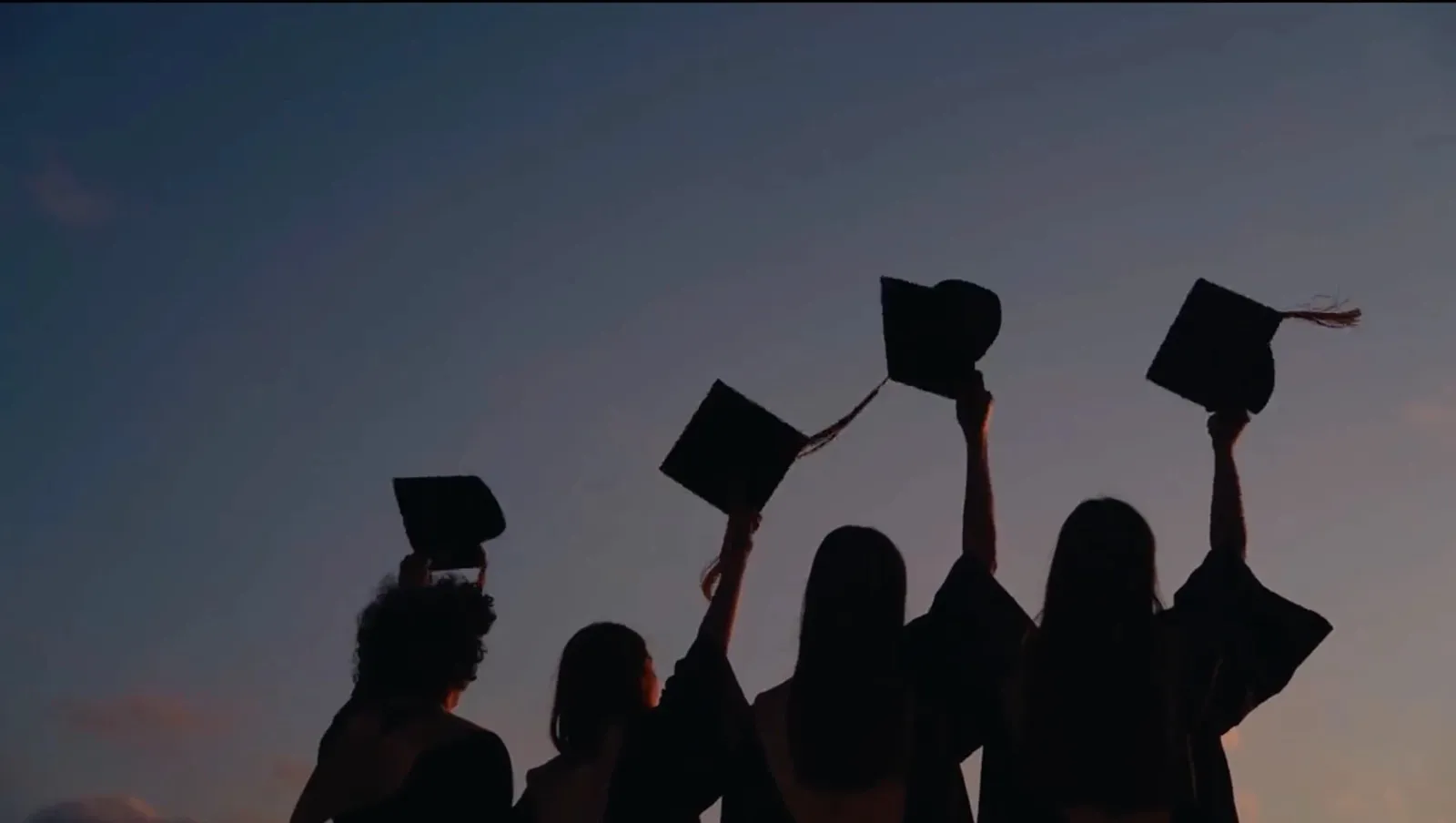 Graduates throwing caps at sunset